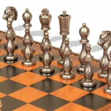 Detal srebrnych figur z filigranowego metalu ustawionych na polach szachownicy