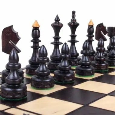 Pièces d'échecs en bois foncé disposées sur l'échiquier pliant