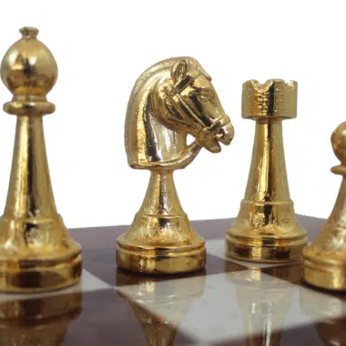 Detal złotych figur: goniec, skoczek, wieża i pion na szachownicy