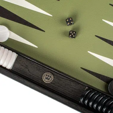 Czarne kostki i biały pion obok grawerowanego medalionu kasety backgammon