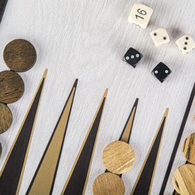 Zbliżenie na drewniane pionki do backgammona oraz białe i czarne kości