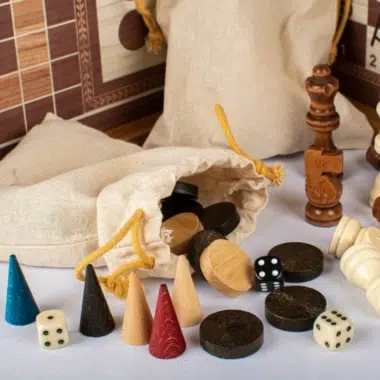 Pionki do backgammona, kości i figurki szachowe ułożone przed woreczkami