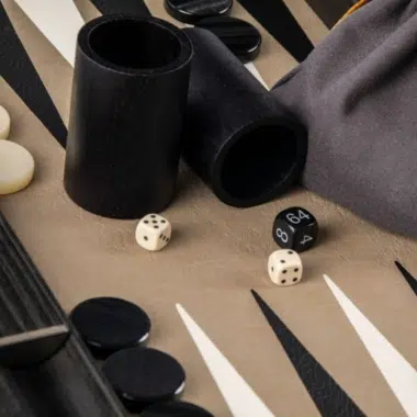 Drewniane kubki do kości i woreczek z tkaniny na planszy do backgammona
