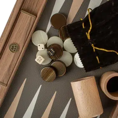 Pionki, kości i woreczek z weluru na planszy do backgammona