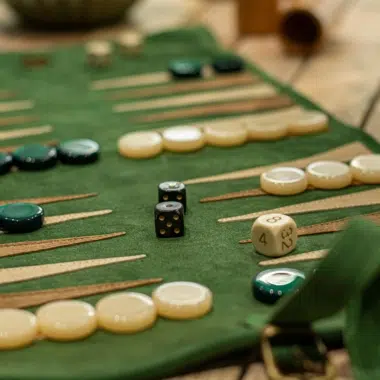 Backgammon z zamszu leśnej zieleni na drewnianym stole, pionki gotowe do gry - Le Palais Des Echecs