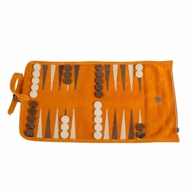 Zwijany backgammon z brązowego zamszu z pionkami i kośćmi, gotowy do gry na kolorowej powierzchni